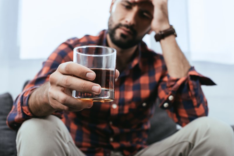 man thinking about taking a drink of alcohol